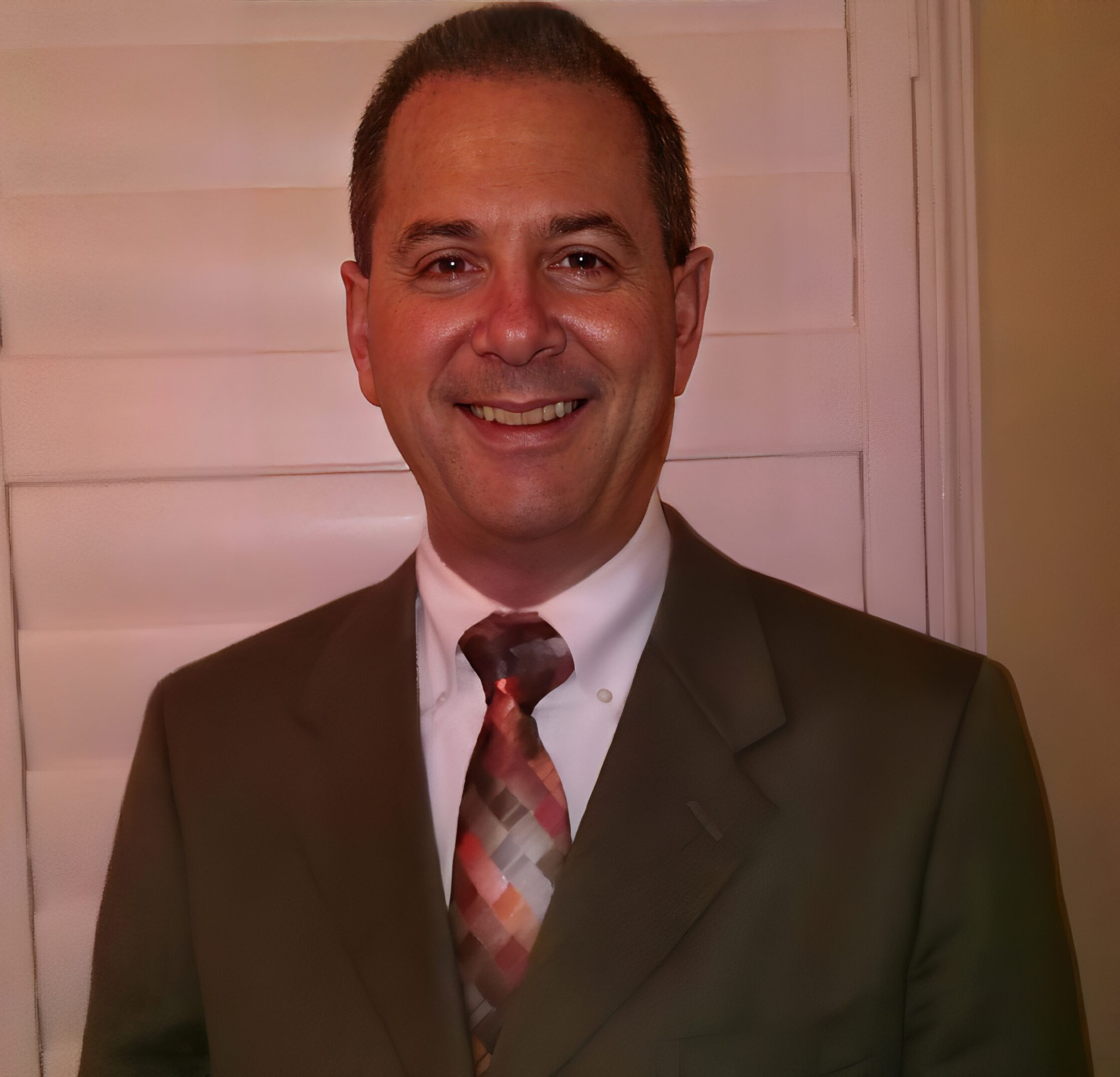 A man in a suit and tie smiling indoors.
