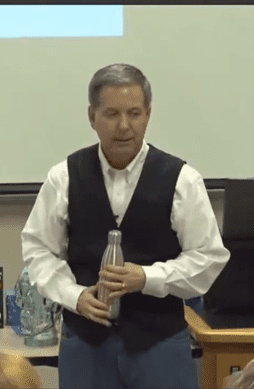 Man demonstrating with a water bottle in a classroom.