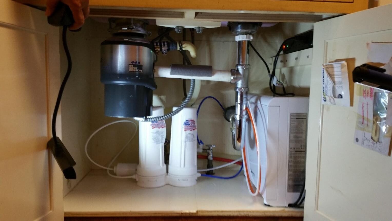 Under-sink plumbing with water filtration system and garbage disposal unit.