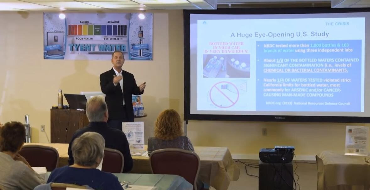 A man presents in front of an audience with a projected slide about heat eye safety.