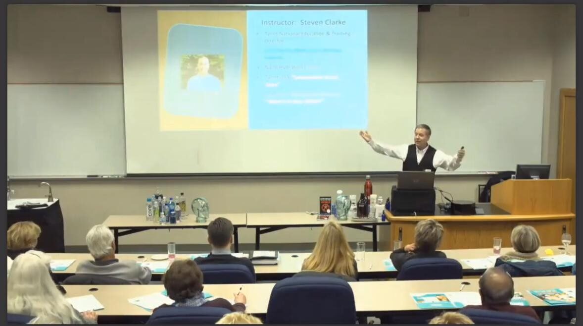 Professor giving a lecture with a book cover projected behind.