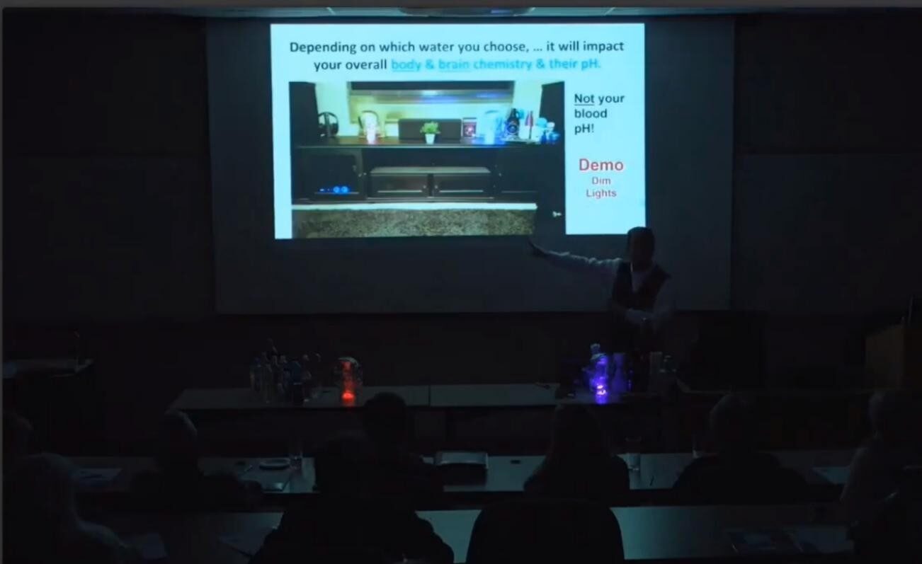 Presenter in a dark room giving a lecture with slides about workspaces.