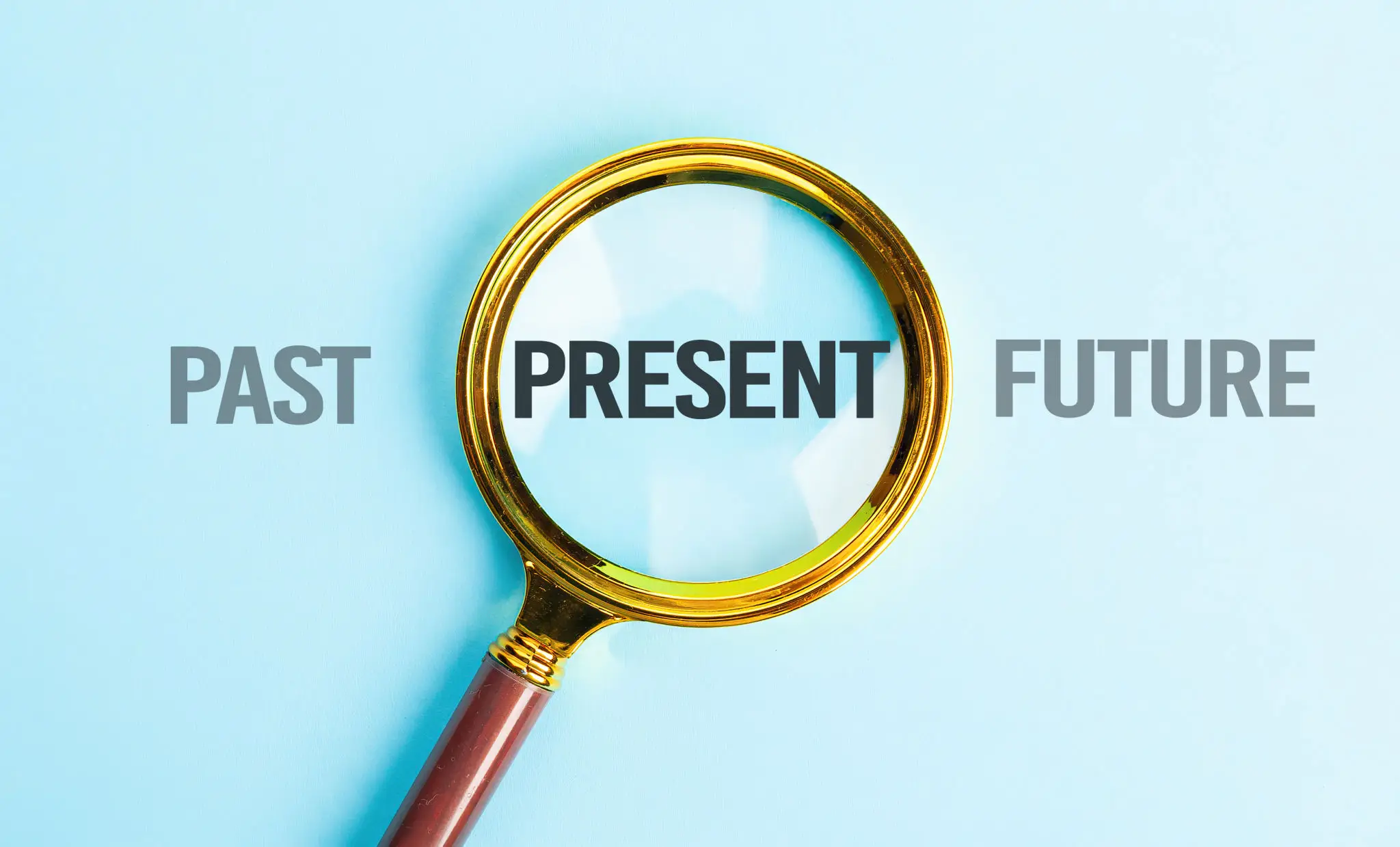Magnifying glass highlights the word 'PRESENT' between 'PAST' and 'FUTURE'.