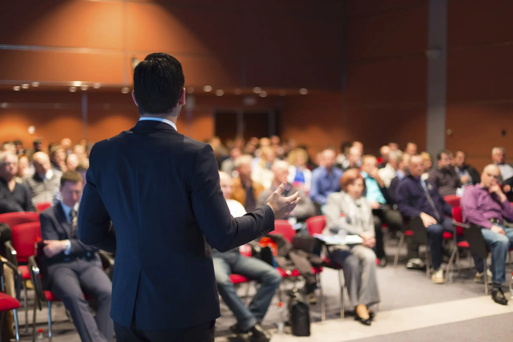 A speaker addressing an attentive audience in a conference room.