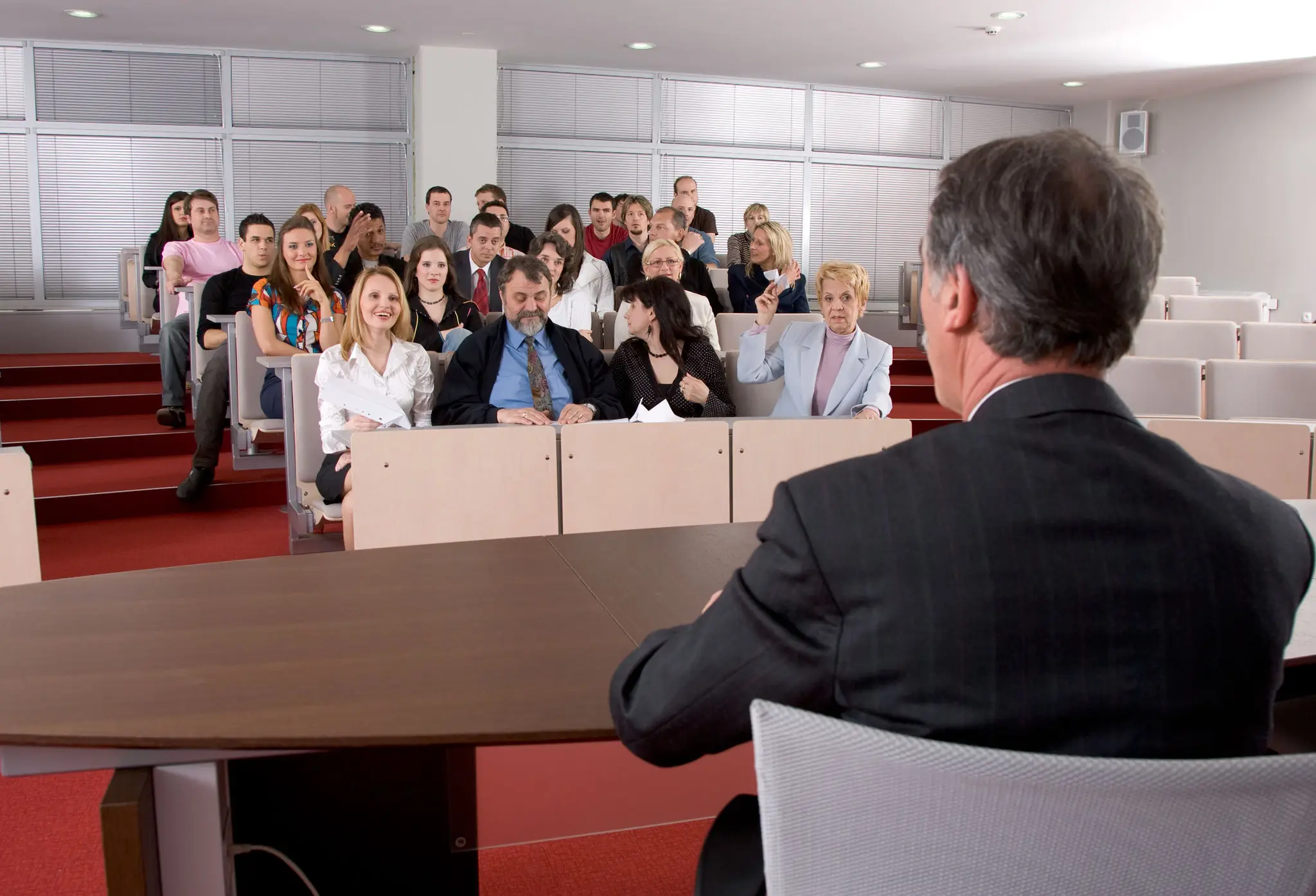 A speaker addressing a large audience in a conference room.